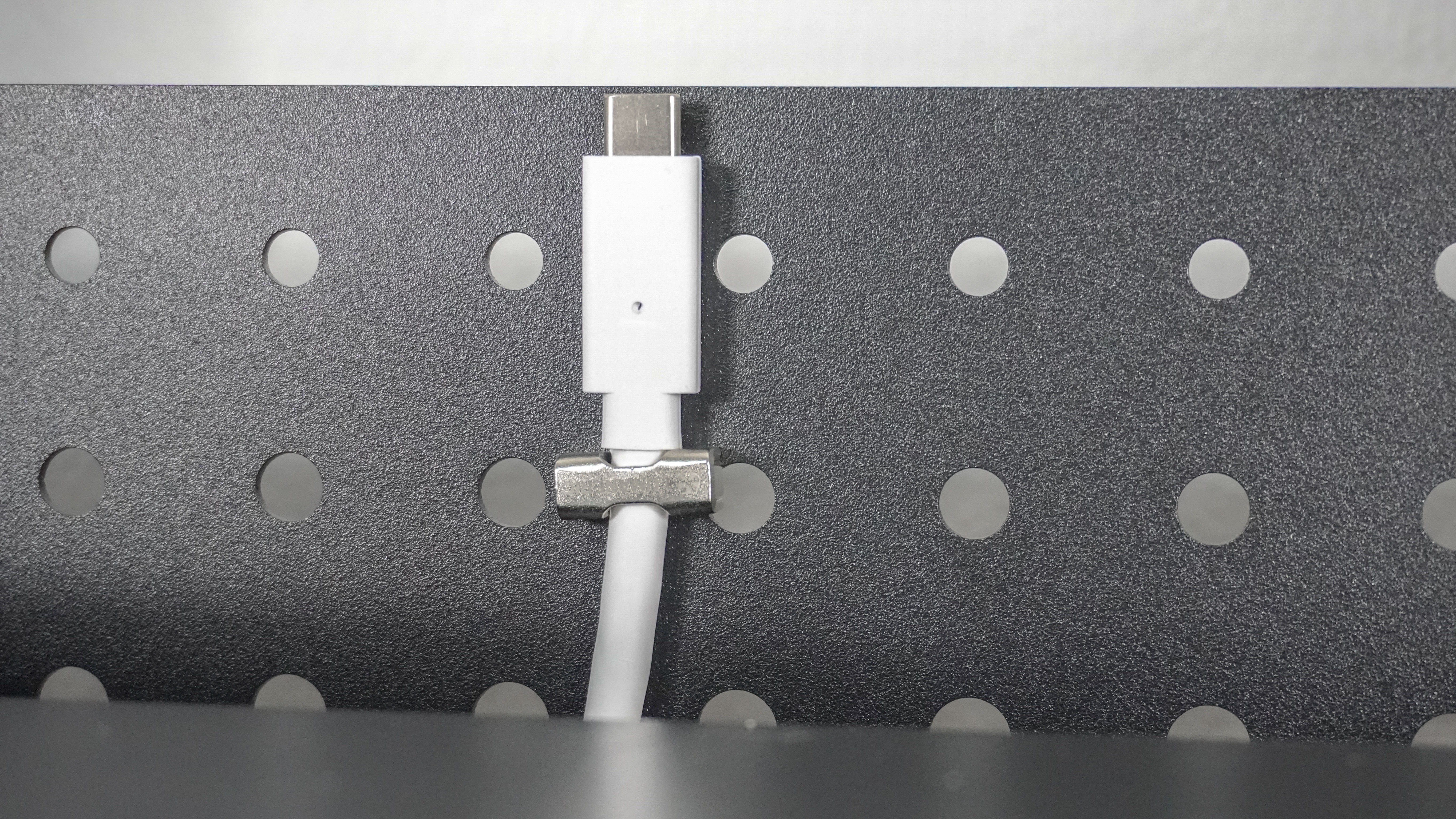 A close-up shot showing a cable attached to the Herman Miller Coyl Gaming Desk's optional shroud using a magnetic clip