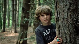 A still from The Wretched on Netflix showing Dillon (Blane Crockarell) hiding behind a tree