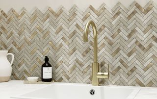 mosaic gold and cream herringbone tiled splashback behind kitchen sink with gold tap