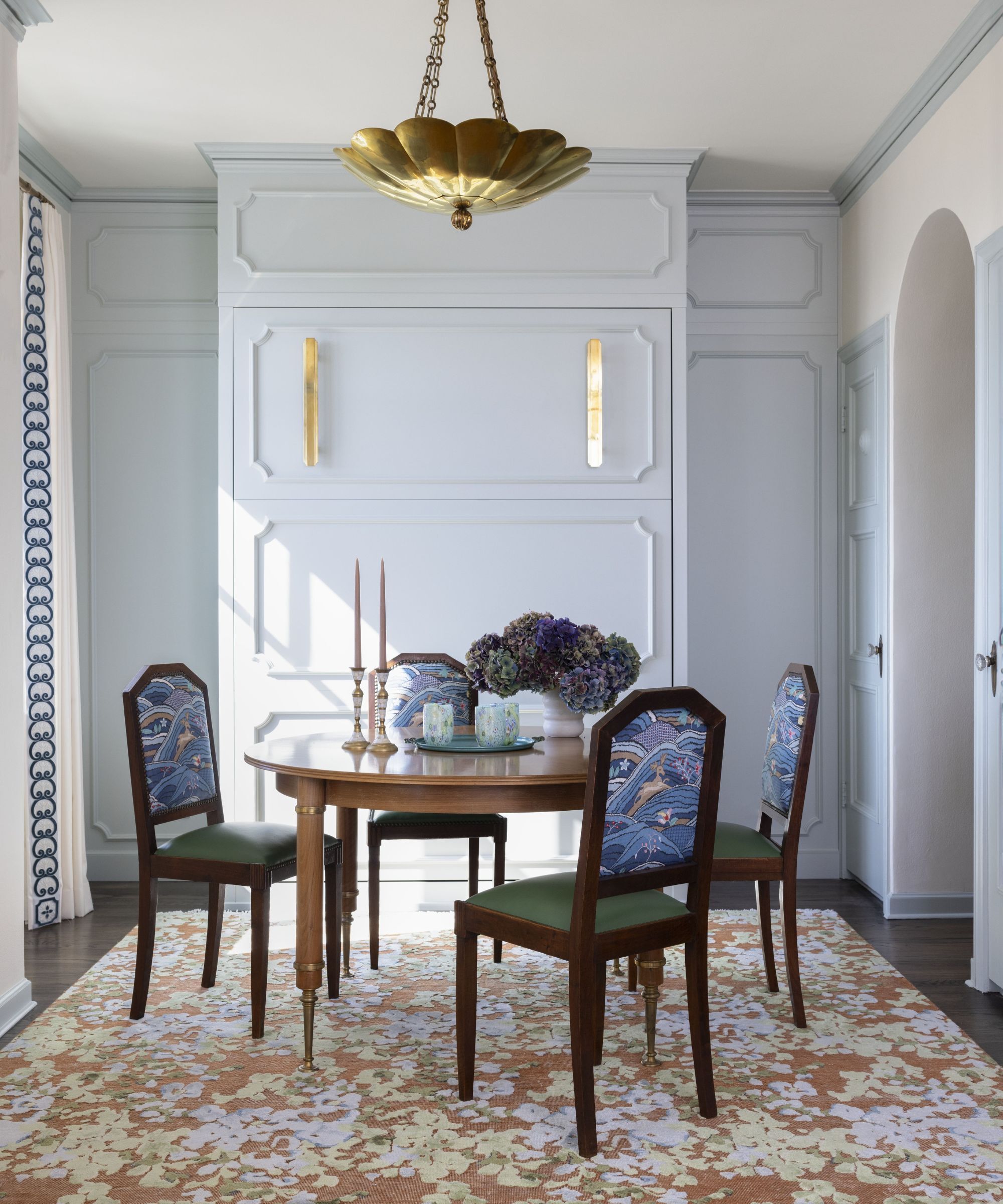 dining room complete with a circular wooden table and wooden chairs upholstered in a blue and green fabrics. 