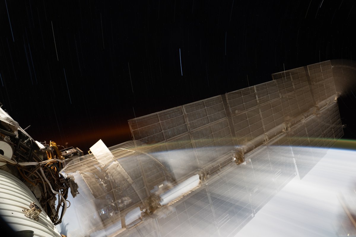 Un panel solar de la estación espacial, que parece transparente tal como está en una pila de fotos y el panel se estaba moviendo en ese momento. Abajo hay nubes de la Tierra que pasan rápidamente.