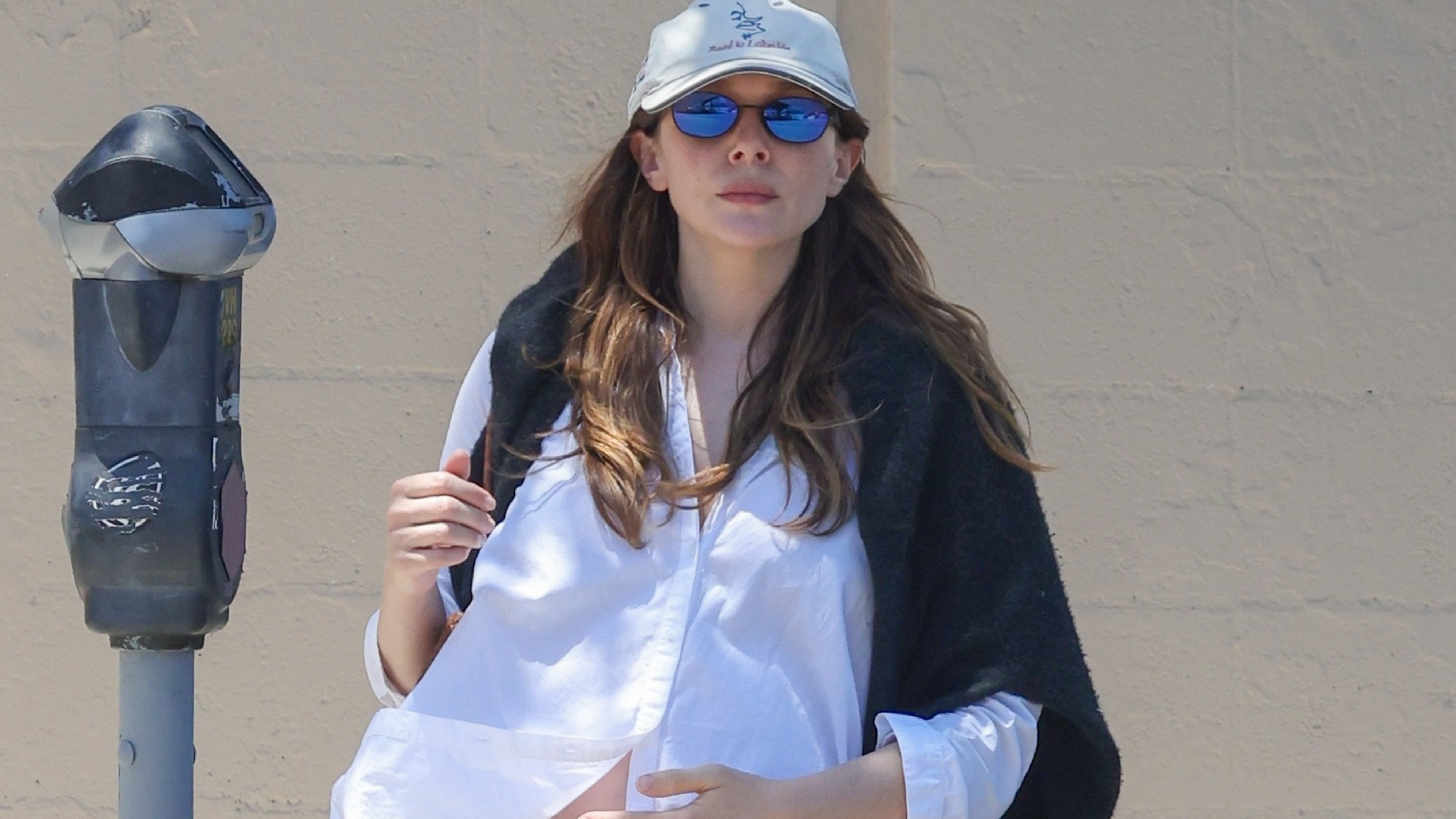 Elizabeth Olsen leaving lunch at All Time Restaurant in Los Angeles wearing a white button-down shirt, eyelet-trim pants, and black loafers.