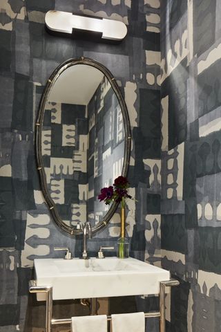 monochromatic style wallpaper in powder room with chrome fixtures, white marble basin, mirror and light