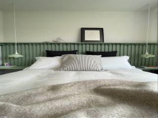 green bedroom with wood panelling behind the bed