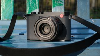 A Leica Q3 43 camera on a blue bench in bright sunlight