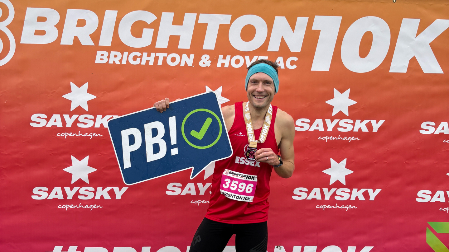 Man holding a PB sign at Brighton 10K