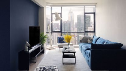 living room with white walls and one blue feature wall, blue sofa and skyline views