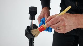 Using a paintbrush to clean a cymbal arm