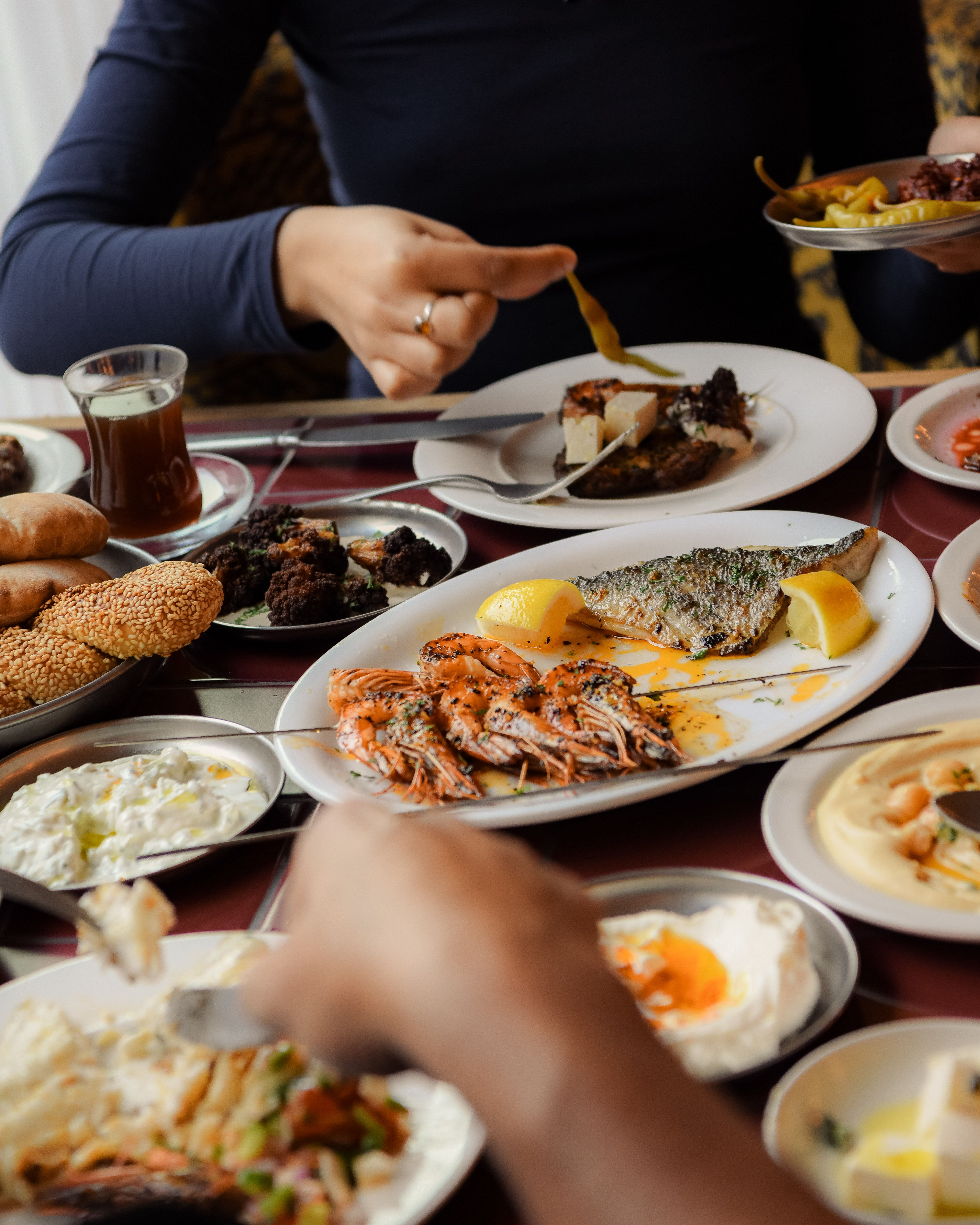 Food and lifestyle shots of a restaurant depict colorful, made-to-share food platters being handled by guests in a warmly decorated, high-end yet playful setting.