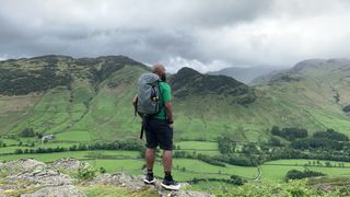 A hiker in a green shirt looks at the view