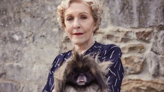 Patricia Hodge in a dark dress as Mrs Pumphrey holds Pekinese Tricki Woo in All Creatures Great and Small.