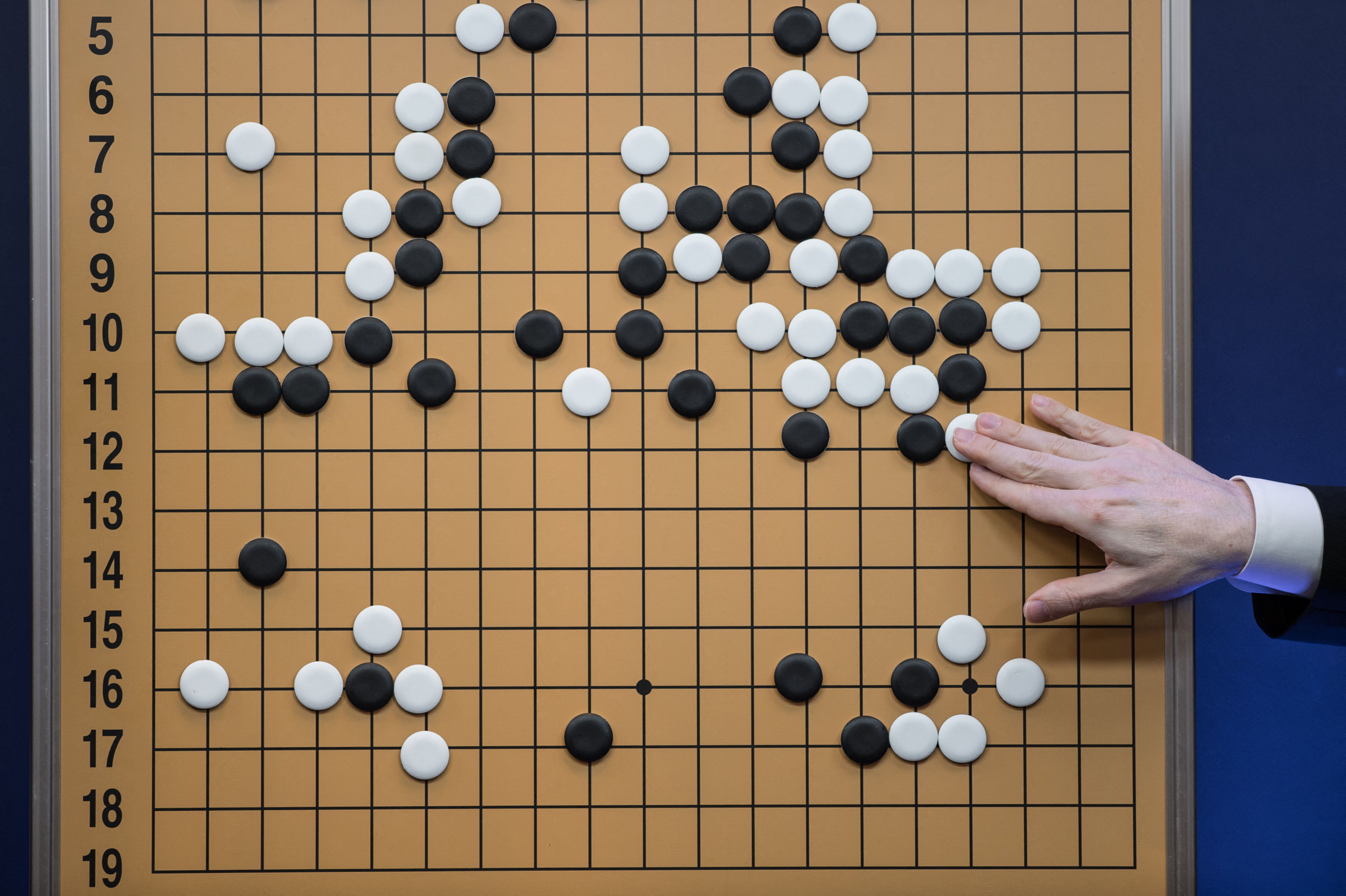 A commentator in a media room positions pieces forming a replica of a game between 'Go' player Lee Sedol and Google DeepMind's AlphaGo AI system, in Seoul on March 13, 2016.