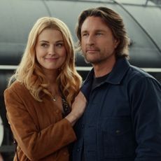 alexandra breckenridge as mel and martin henderson as jack embrace in front of a train at a train station while meeting a mysterious woman in a new still from virgin river season 7