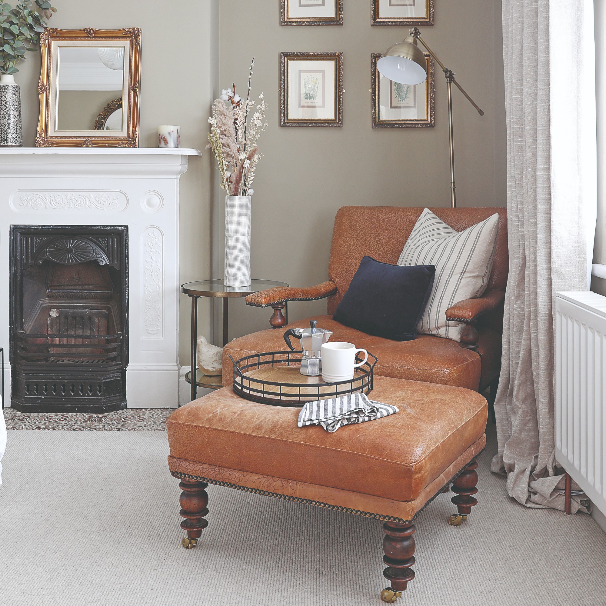 A neutral living room with an off-white carpet and a brown leather armchair with a matching ottoman in the corner