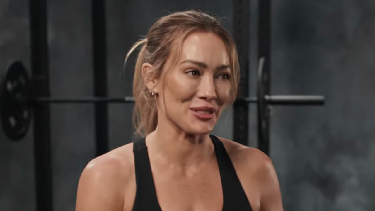 Hilary Duff talking about fitness next to a bench in gym in Ladder video. 