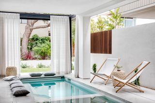 covered patio with mini pool, deckchairs, white scheme, drapes, cushions