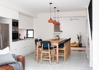 White kitchen-diner with terracotta pendant lights over oak dining table