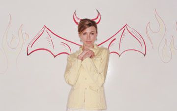 Woman against whiteboard illustrated with devil wings and flames