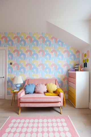 Rainbow wave wallpaper behind pink couch in fun bedroom