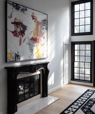 living room fireplace with white walls and bright contemporary artwork and black framed windows