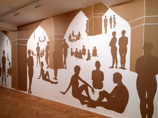 White wall covered with brown paper silhouettes of people and archways