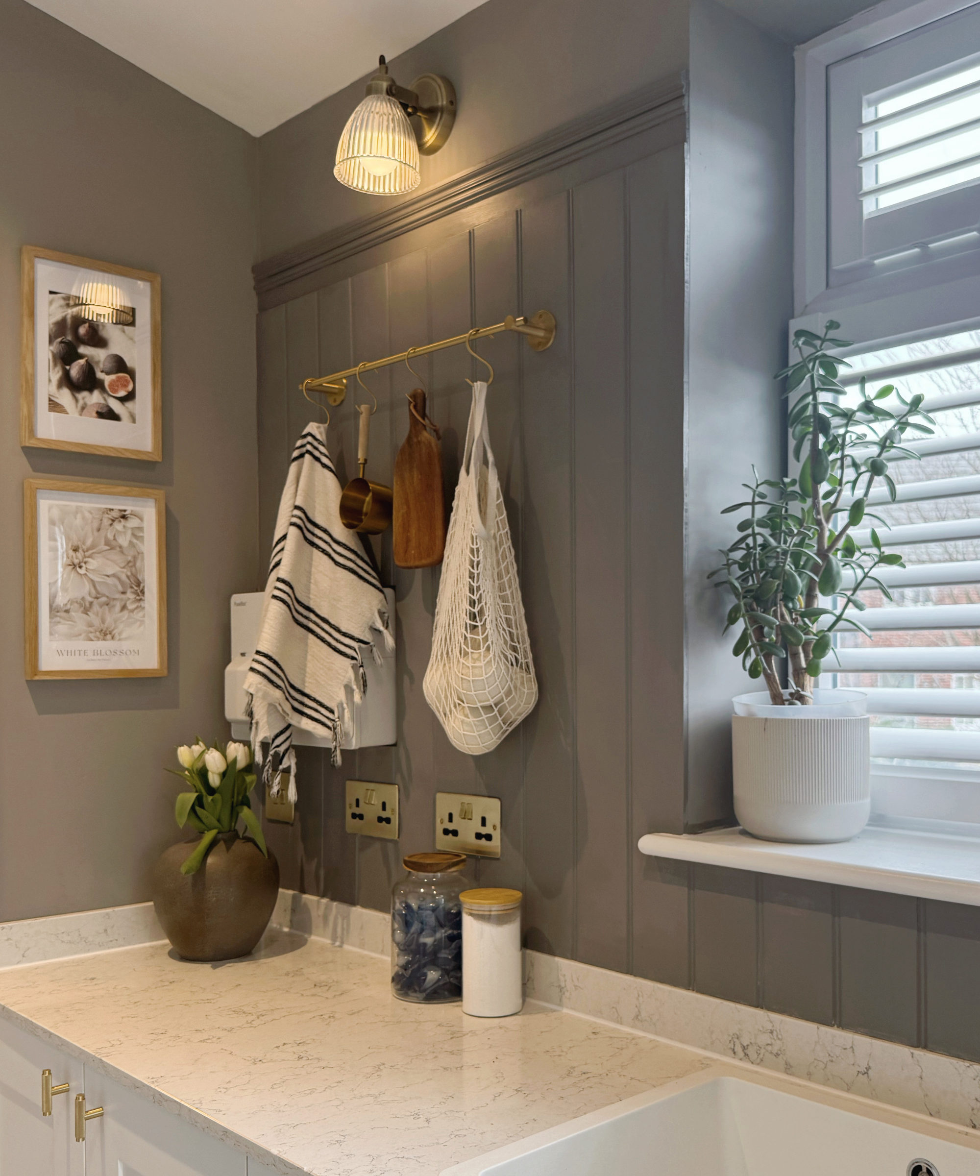 Grey beadboard panelling above a marble-style worktop next to a shuttered window