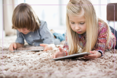 a young boy and girl using tablets on the floor