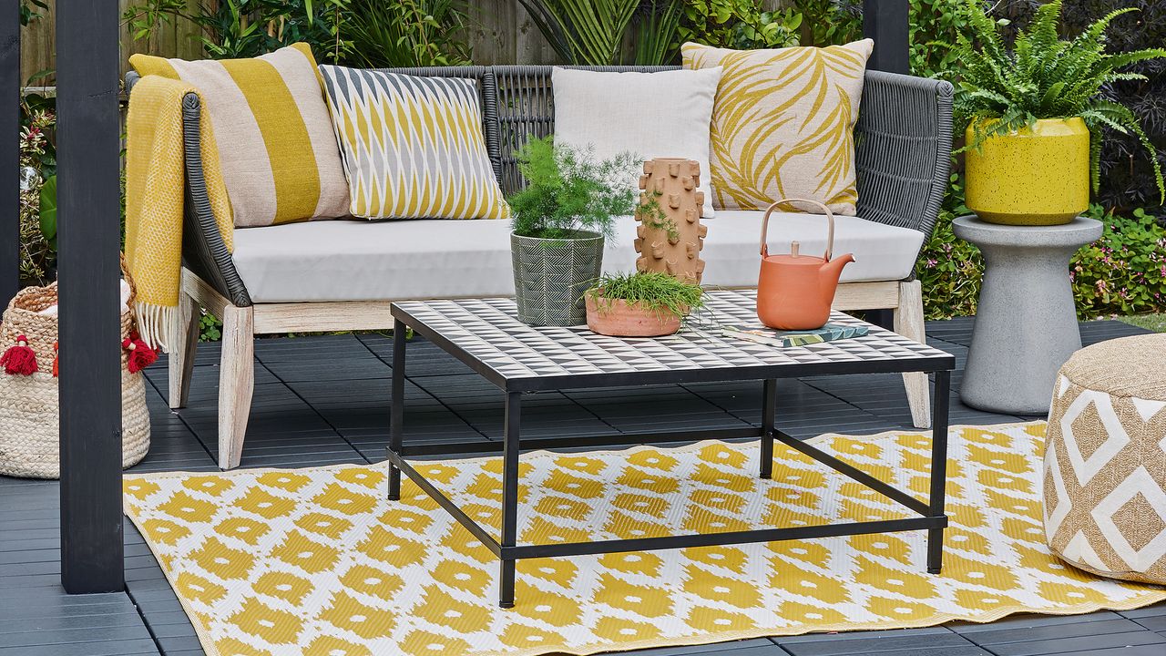 Black and yellow patio with white cushions and yellow outdoor rug