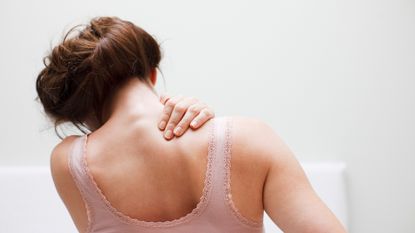 Woman clasps her back in pain