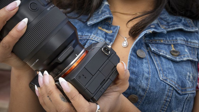 A close-up of the Tamron-Link on a lens in a photographer's hands