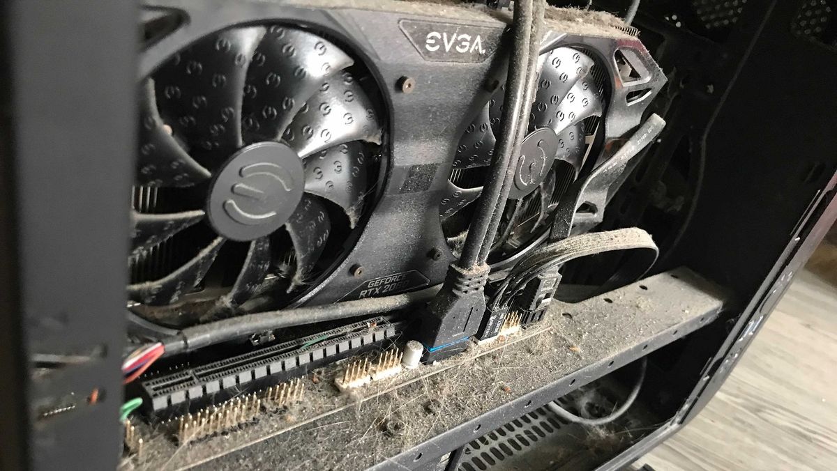 The interior of a computer case with tons of dust on the fans and case.