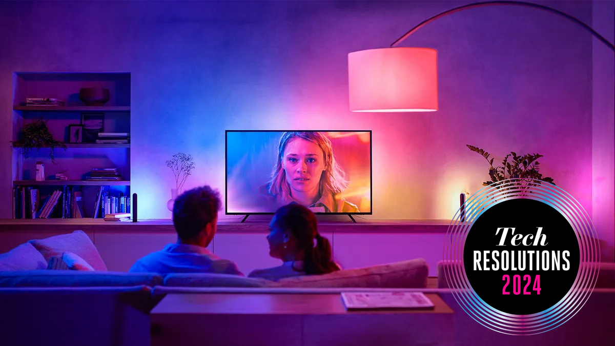 A couple sitting on the sofa in front of the TV surrounding by smart lights
