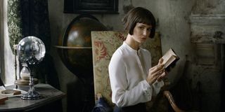 Katherine Waterston reading a book and looking ominously toward the camera in Fantastic Beasts: The Crimes of Grindelwald.