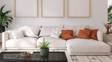 White L-shape couch with orange cushions and black table with plants