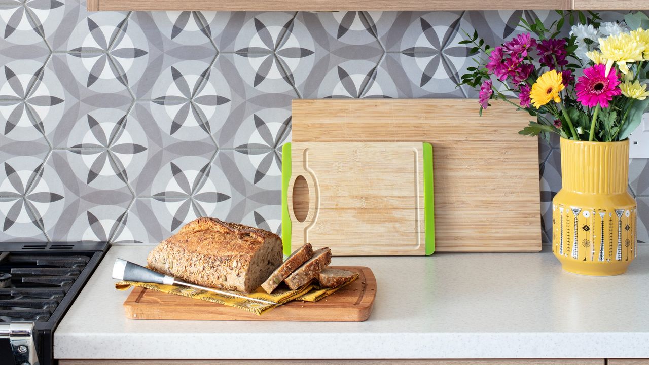 A kitchen worktop with a loaf of bread on a wooden cutting board