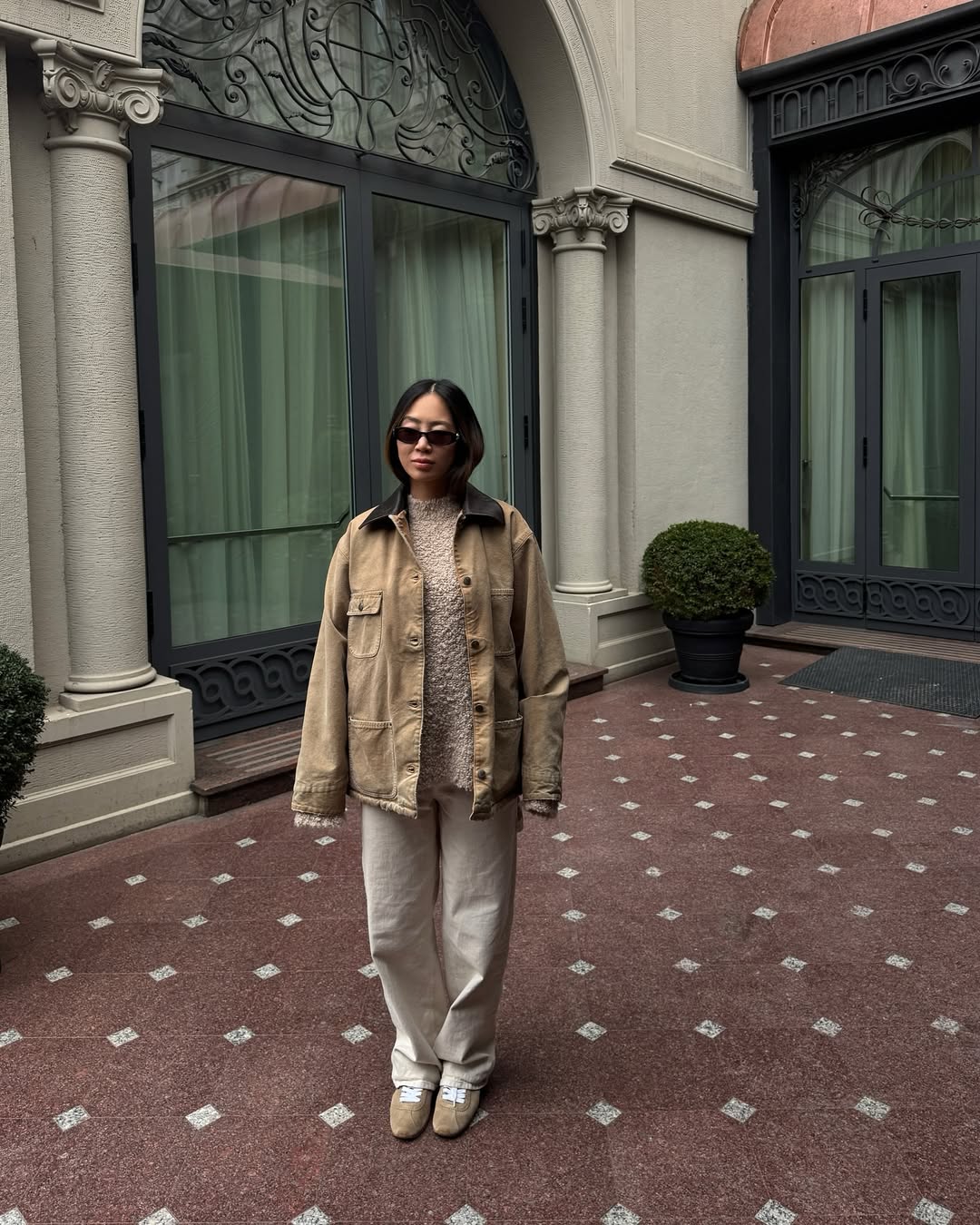 Influencer Aimee Song in a barn jacket, tan trousers, and suede sneakers.