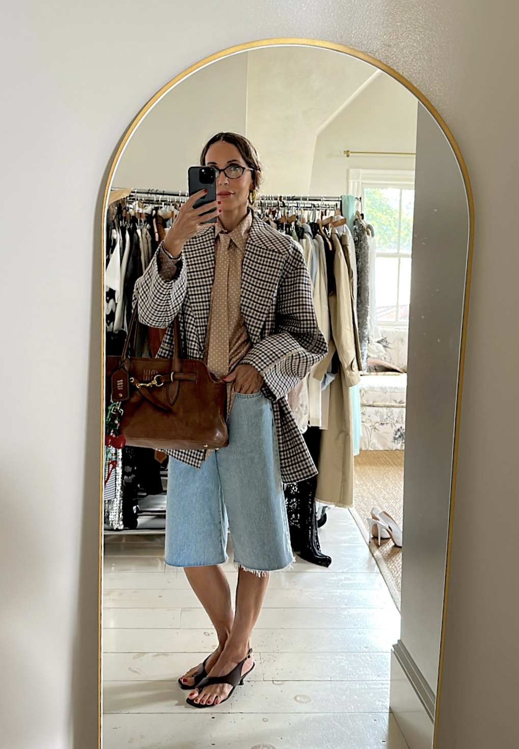 Larissa Mills wearing a checkered blazer, denim shorts, and heels