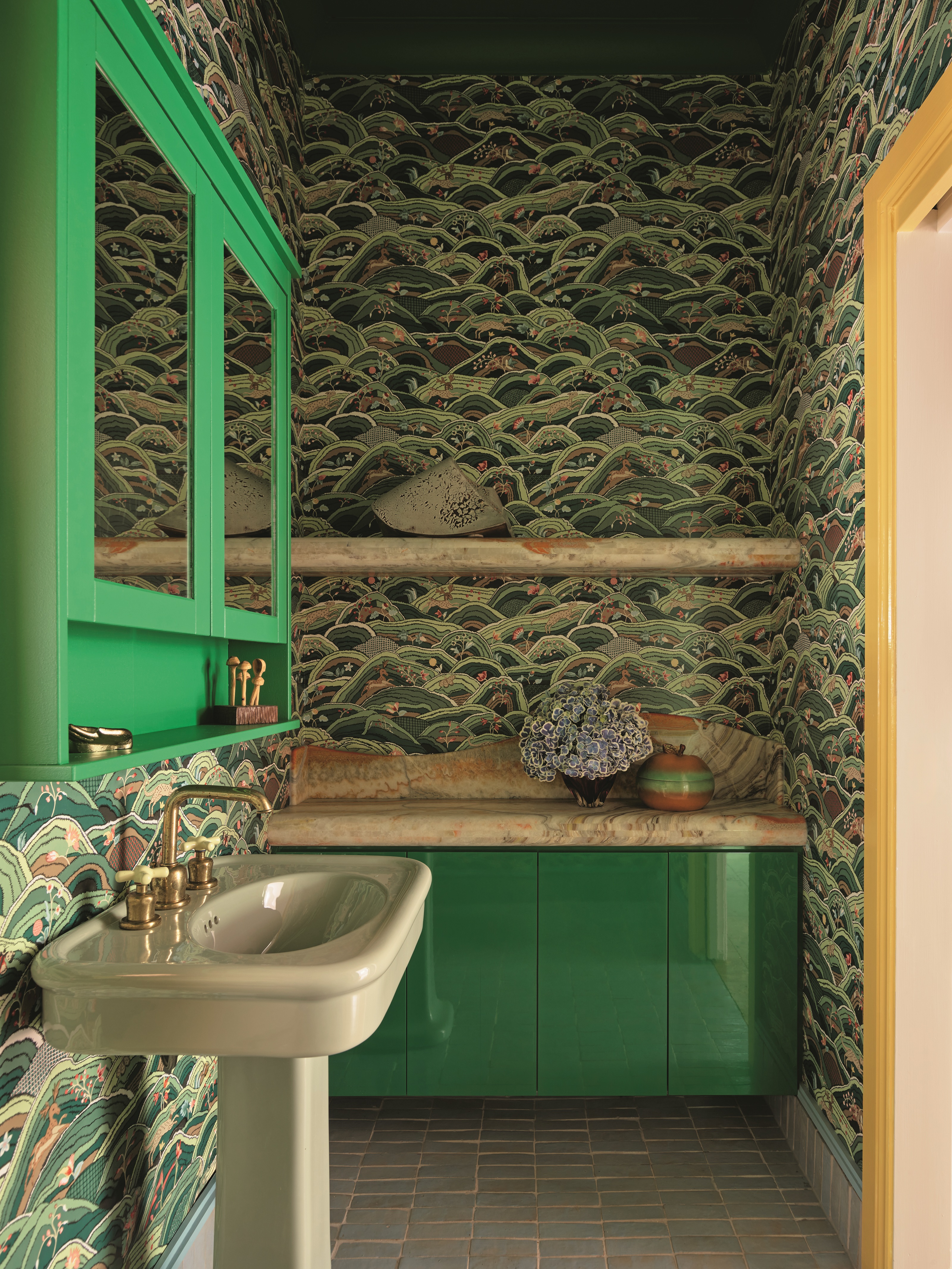 a green bathroom with a patterned wallpaper, a green gloss cabinet and a light green pedestal basin