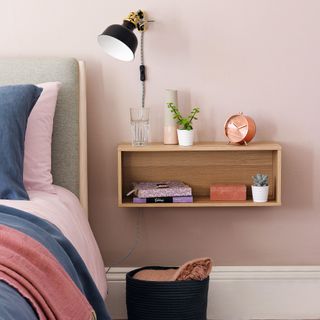 Relaxed Scandi style bedroom with pale pink walls, blue and darker pink bedding and wood bedside table with black accent anglepoise lamp