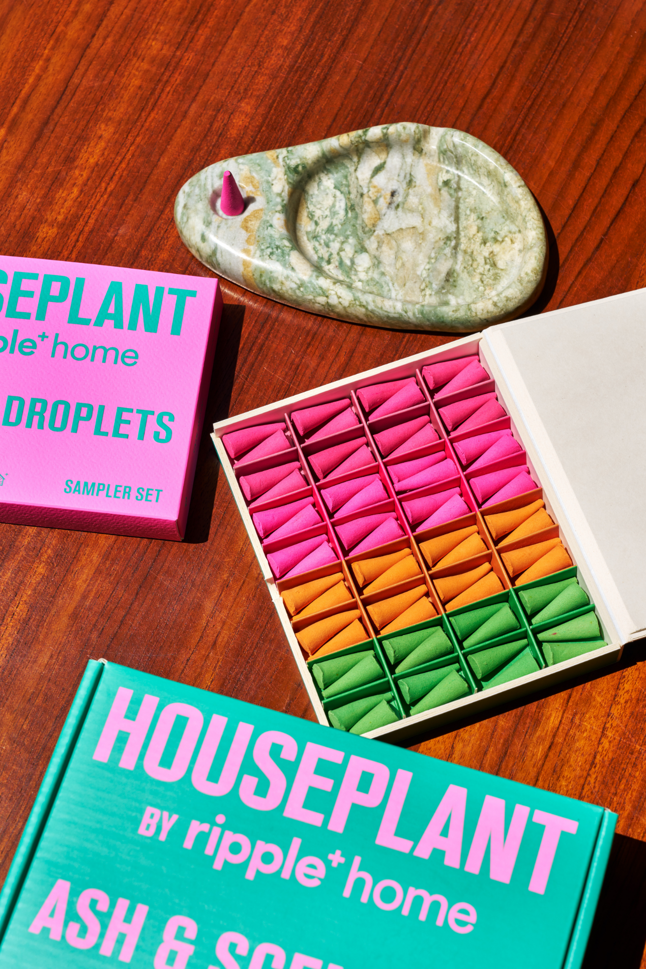 A box of colorful incense droplets by a green marble holder
