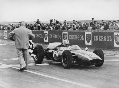 Australian racing driver Jack Brabham takes the chequered flag to win the French Grand Prix at Rheims in a Cooper-Climax T53, 3rd July 1960.(Photo by /Hulton Archive/Getty Images)
