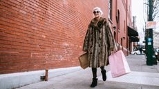 Woman carrying shopping bags past a shop window in the boxing day sales