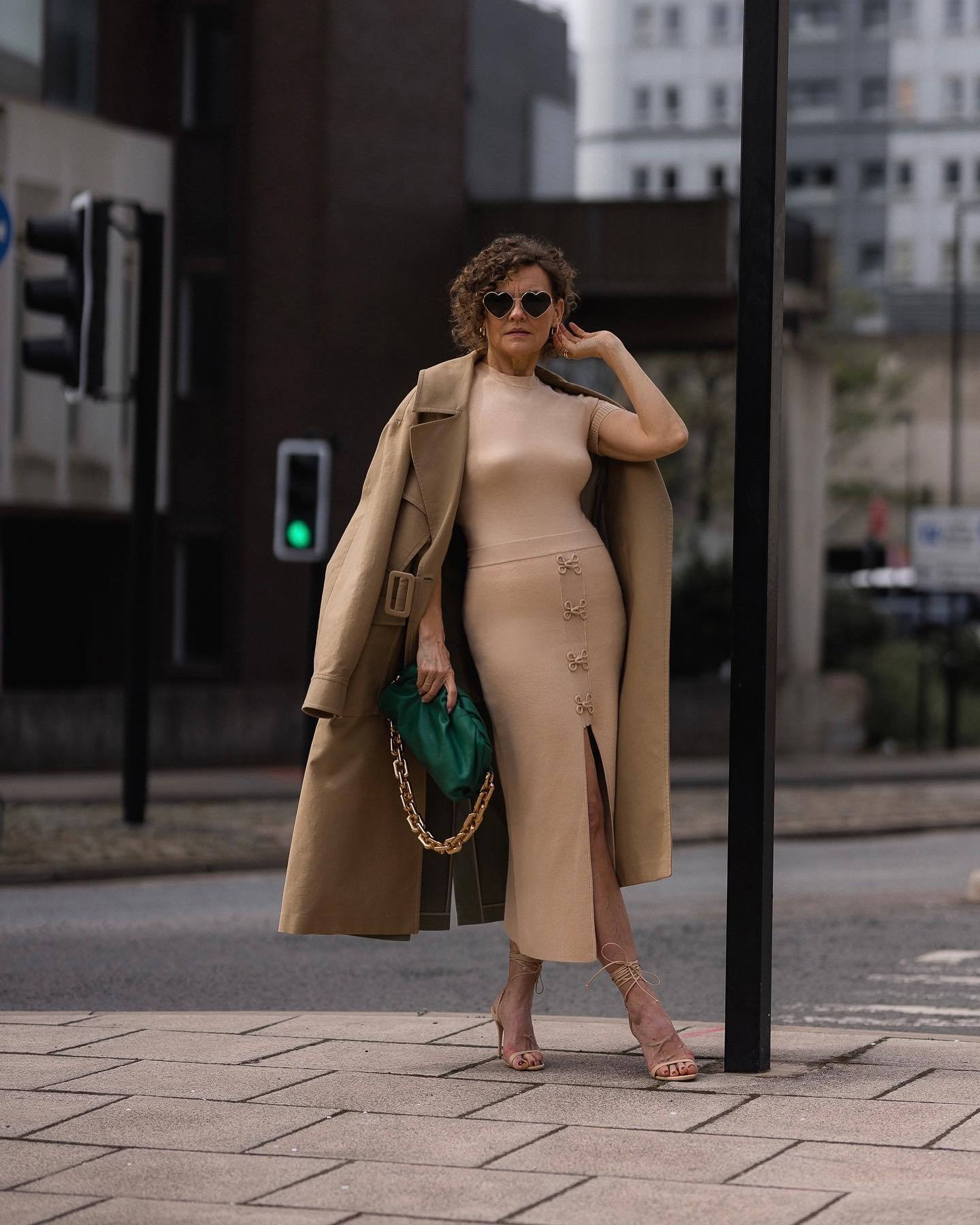 A woman posing outside with an asymmetrical curly bob haircut