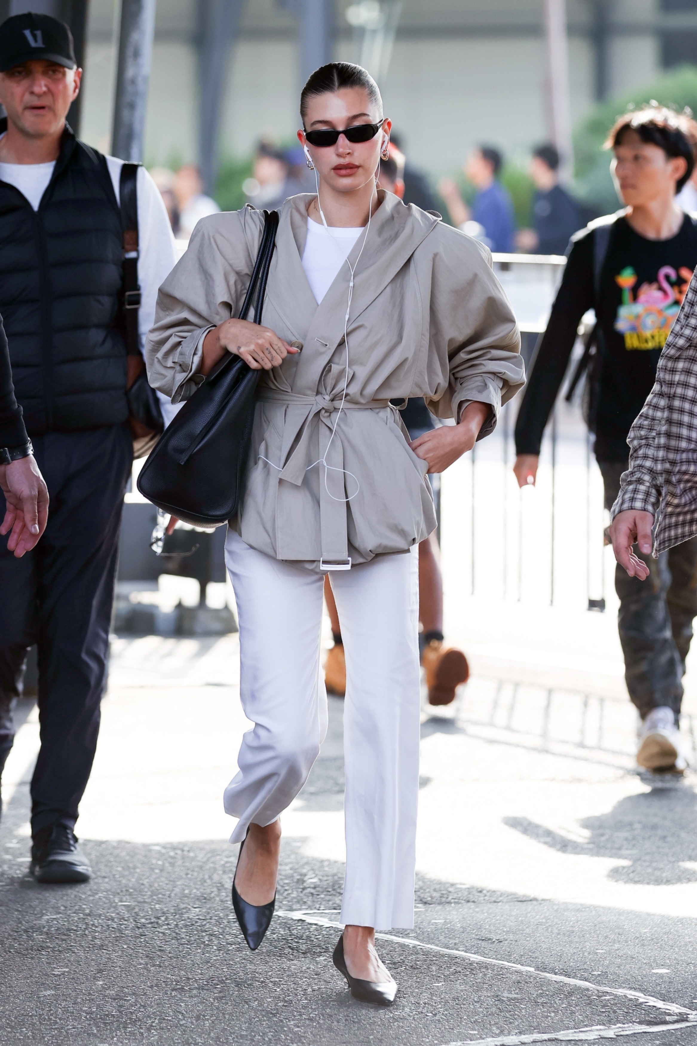 Hailey bieber's summer airport outfit includes a cropped trench coat, white jeans, and the Chanel Maxi Flap Bag Feb 11