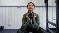 woman in squat position with a dumbbell