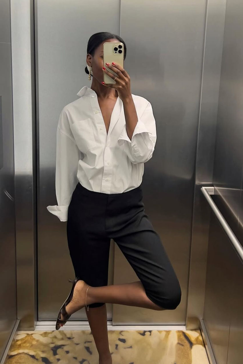a woman wearing a white button-down, black capri pants, and black kitten heels