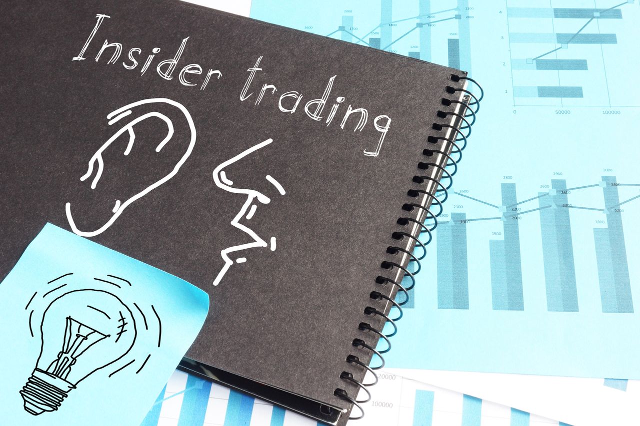 insider trading written on notebook with financial graphs in background