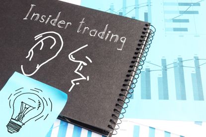 insider trading written on notebook with financial graphs in background