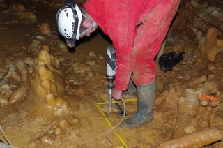 Scientists drill into the stalagmitic floor inside one of the structures, likely created by Neanderthals, in the Bruniquel Cave in France.