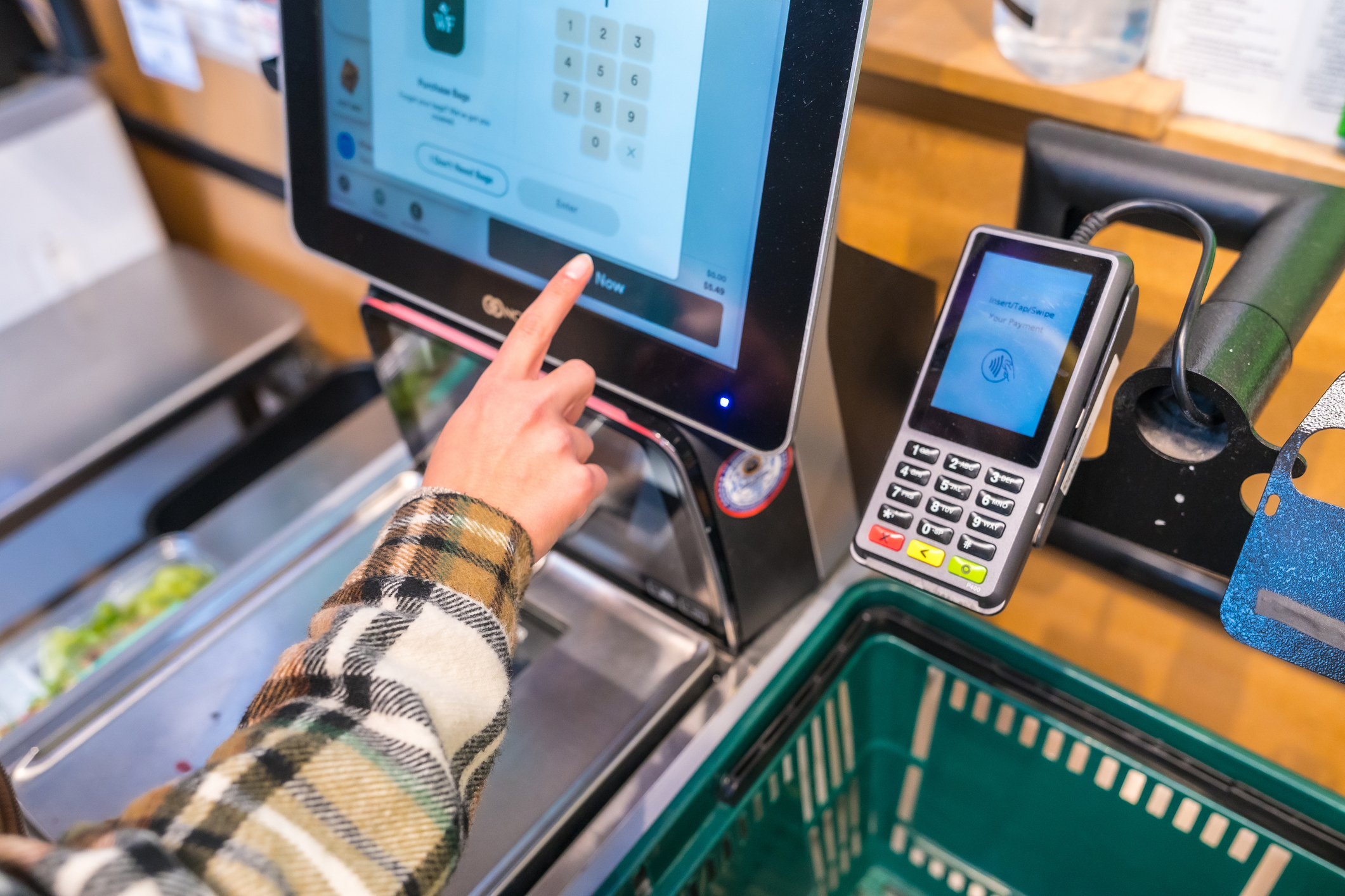 Customer using self-checkout kiosk at grocery store